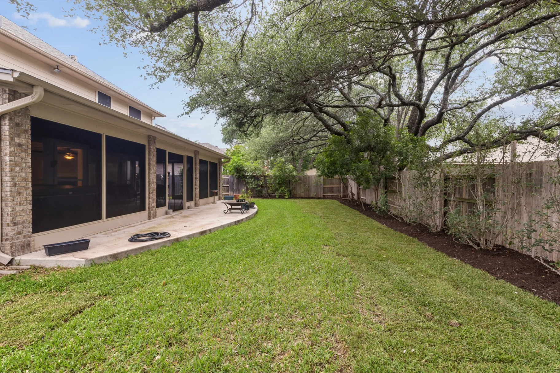 Backyard side view with screened patio and landscaped beds
