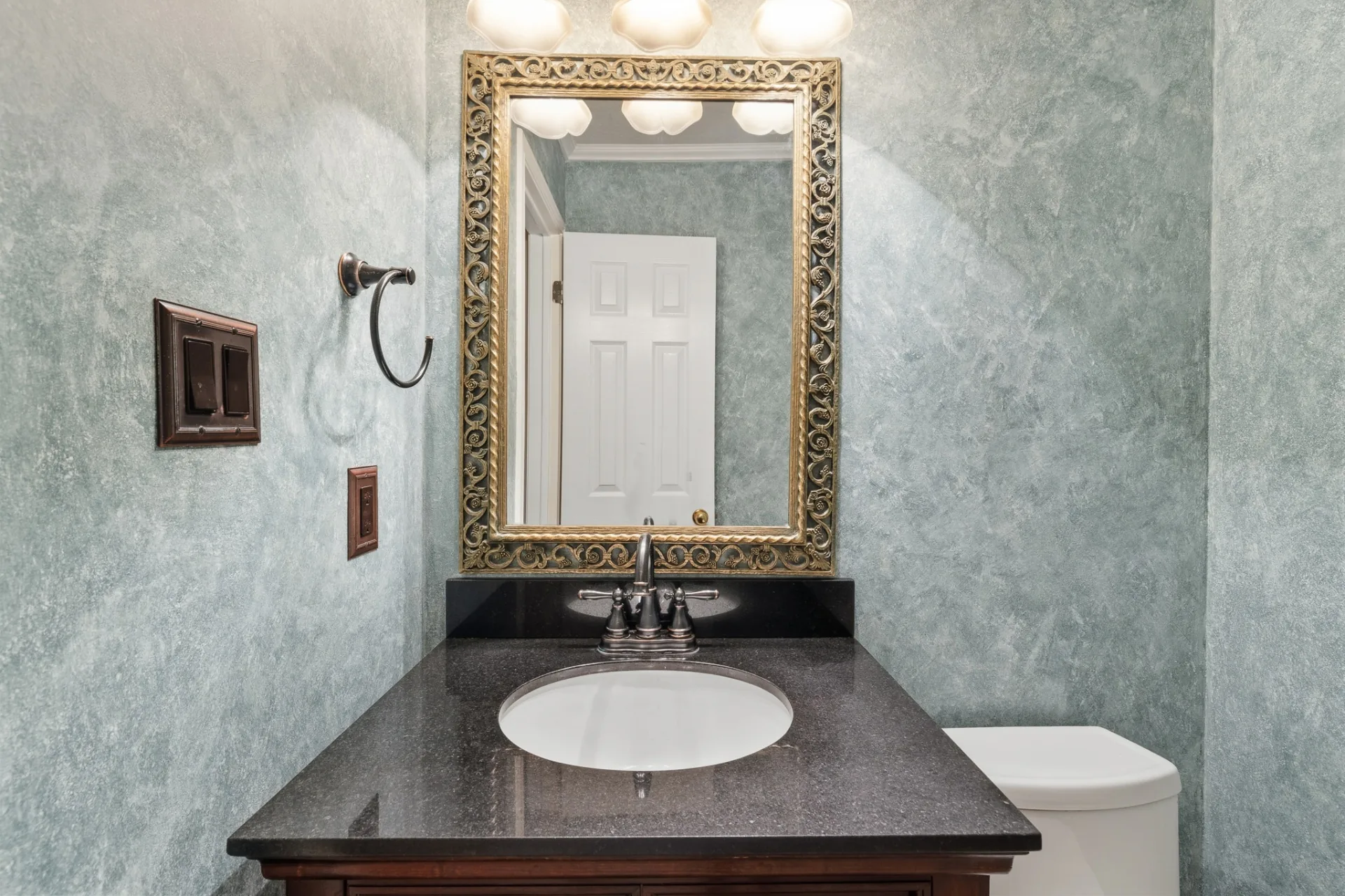Powder bath with granite vanity and ornate mirror