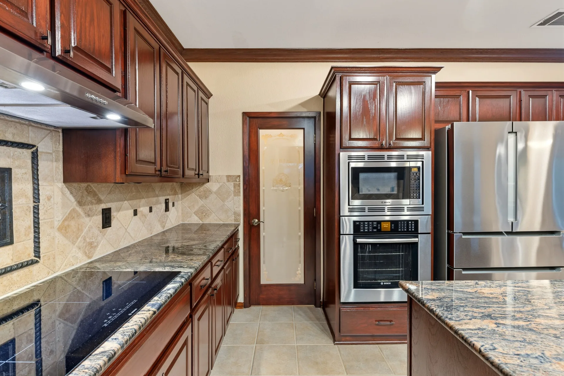 Kitchen detail with Bosch wall ovens, cooktop, and granite surfaces