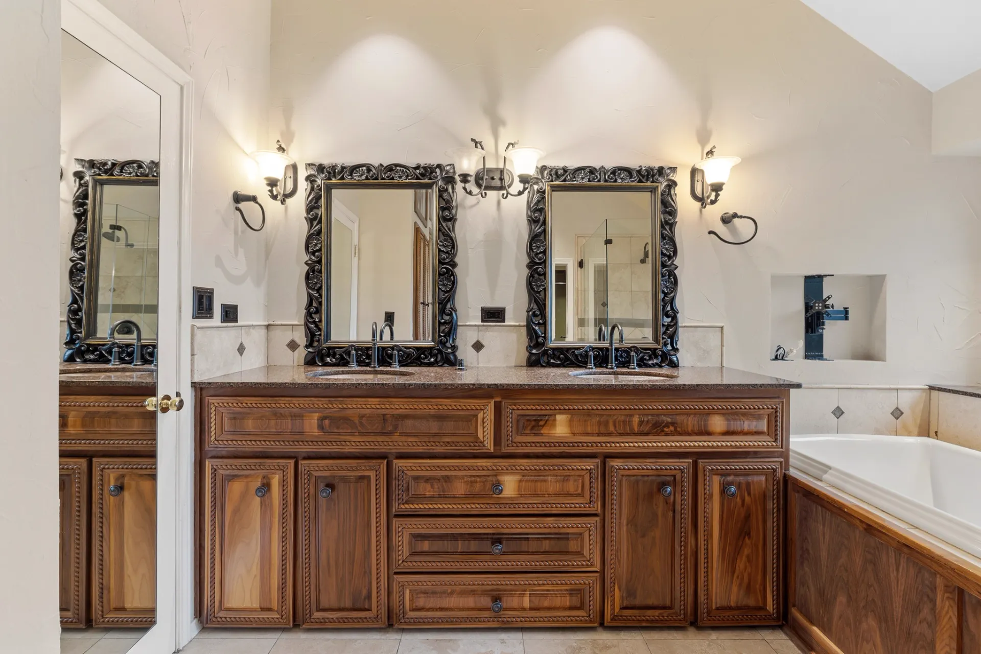 Primary bath double vanity with custom cabinetry and ornate mirrors