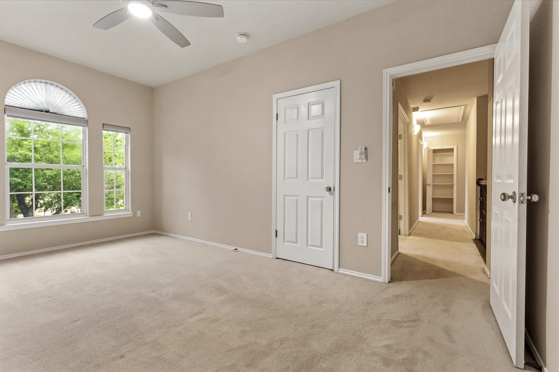 Bedroom view to upstairs hall with linen storage and arched window