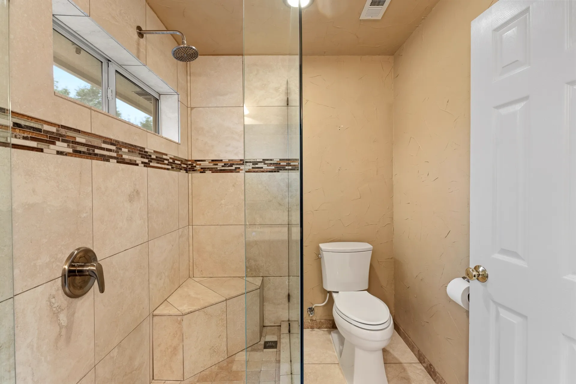 Hall bathroom walk-in shower with travertine tile and glass enclosure